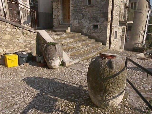 Große Vorratsgefäße aus Maiella-Stein an einer Gasse des historischen Ortskerns