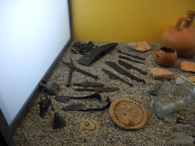 A museum case with tools and pottery