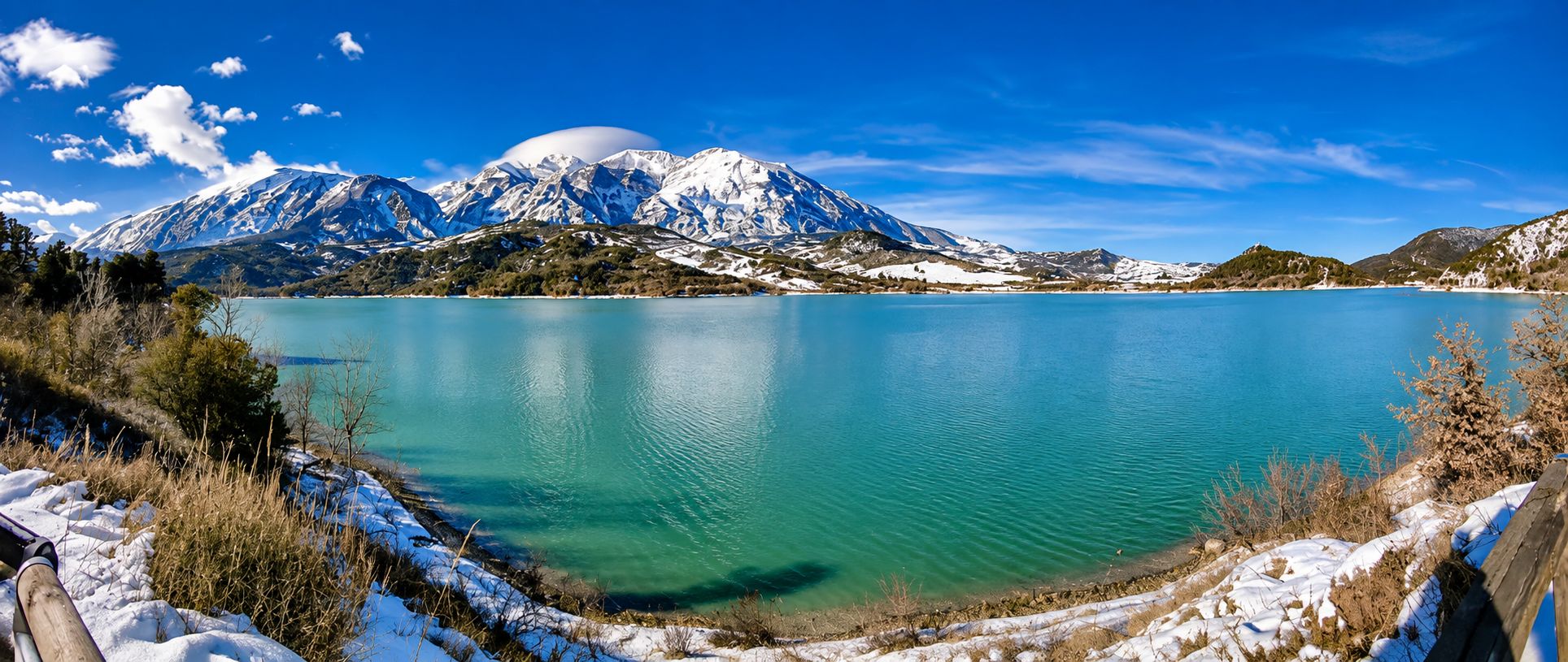 Der See von Casoli mit grünblauem Wasser und der verschneiten Maiella im Hintergrund