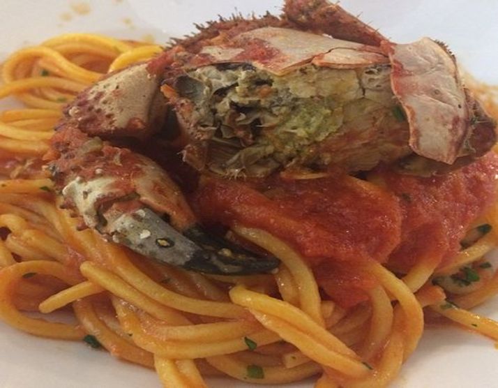 Ein Teller Pasta mit Sauce von „pelosi“: die im Ganzen gegarte Krabbe liegt auf der Pasta, mit Tomatensauce und Petersilie