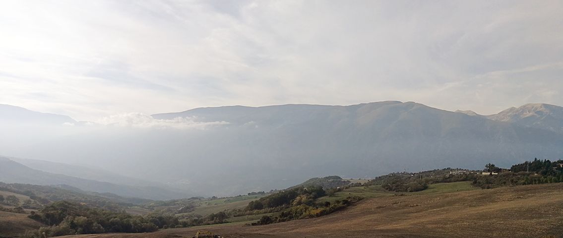 The valley wrapped in haze, with the outlines of the mountains behind